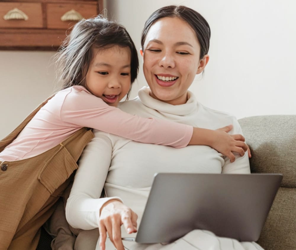 Mother and daughter doing homework together with their laptop at home